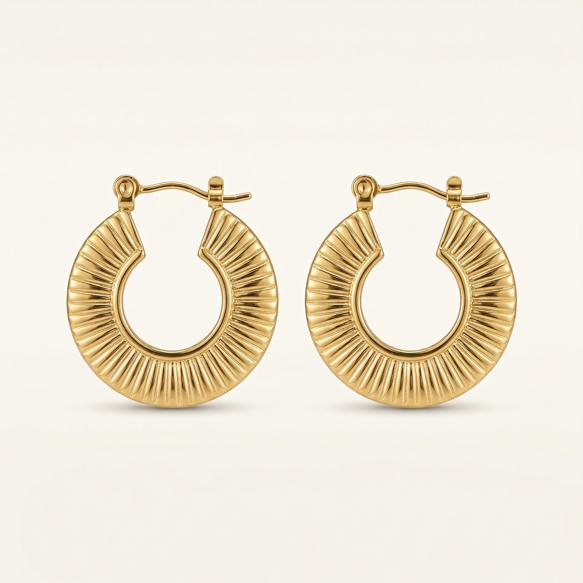Gold hoop earrings on a light beige background