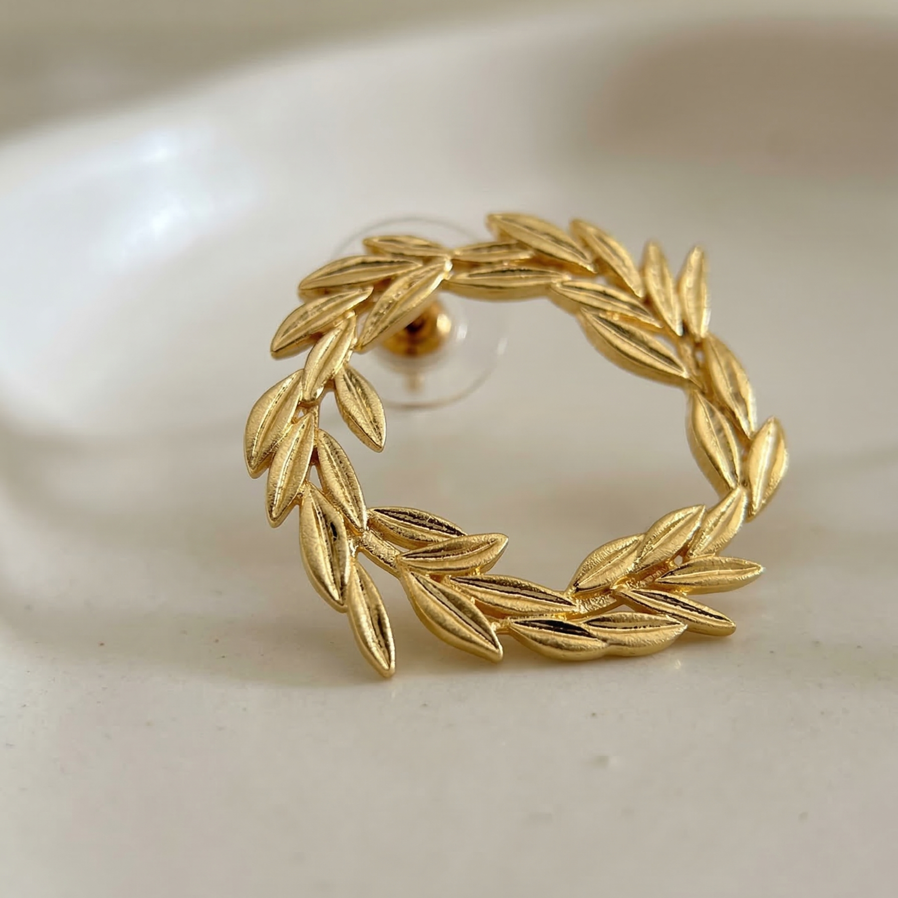 Gold leaf wreath earring on a white background