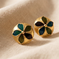 Gold earrings with green gemstones on a beige fabric background
