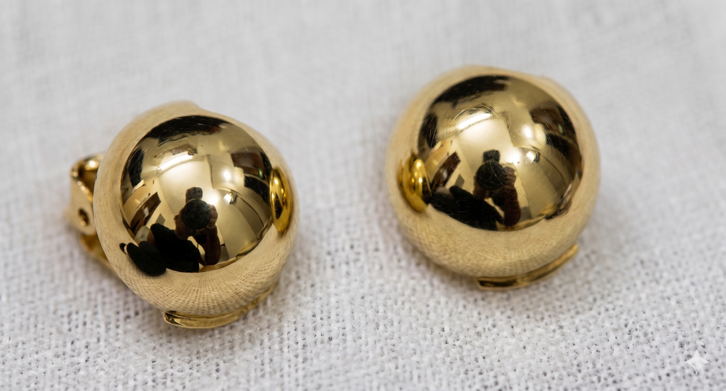 Pair of gold spherical earrings on a textured white background