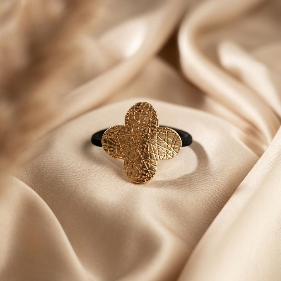 Gold ring with a textured design on a beige fabric background
