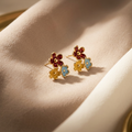 Floral earrings with colored stones on a soft beige background