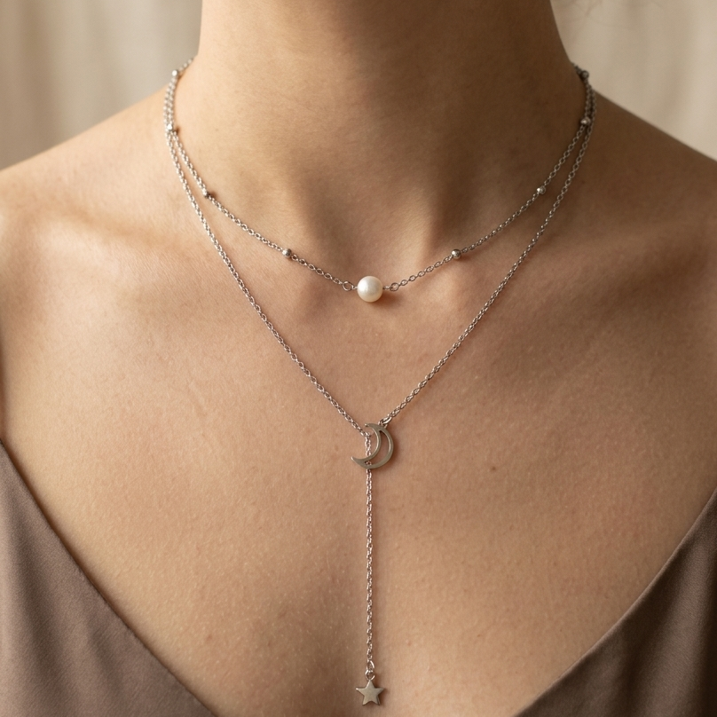Necklace with a pearl pendant and moon-shaped charm on a neutral background