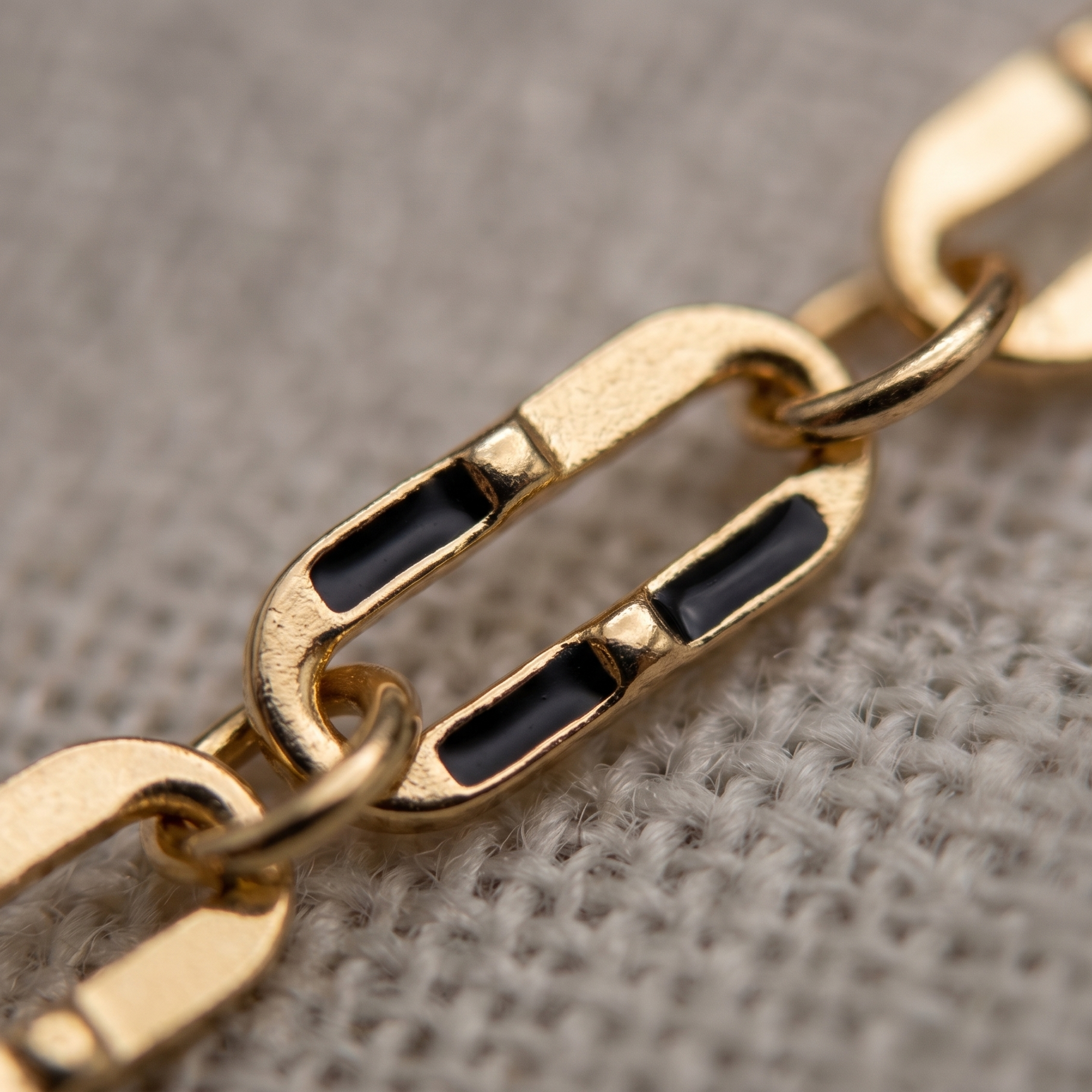 Gold chain with black stones on a textured surface