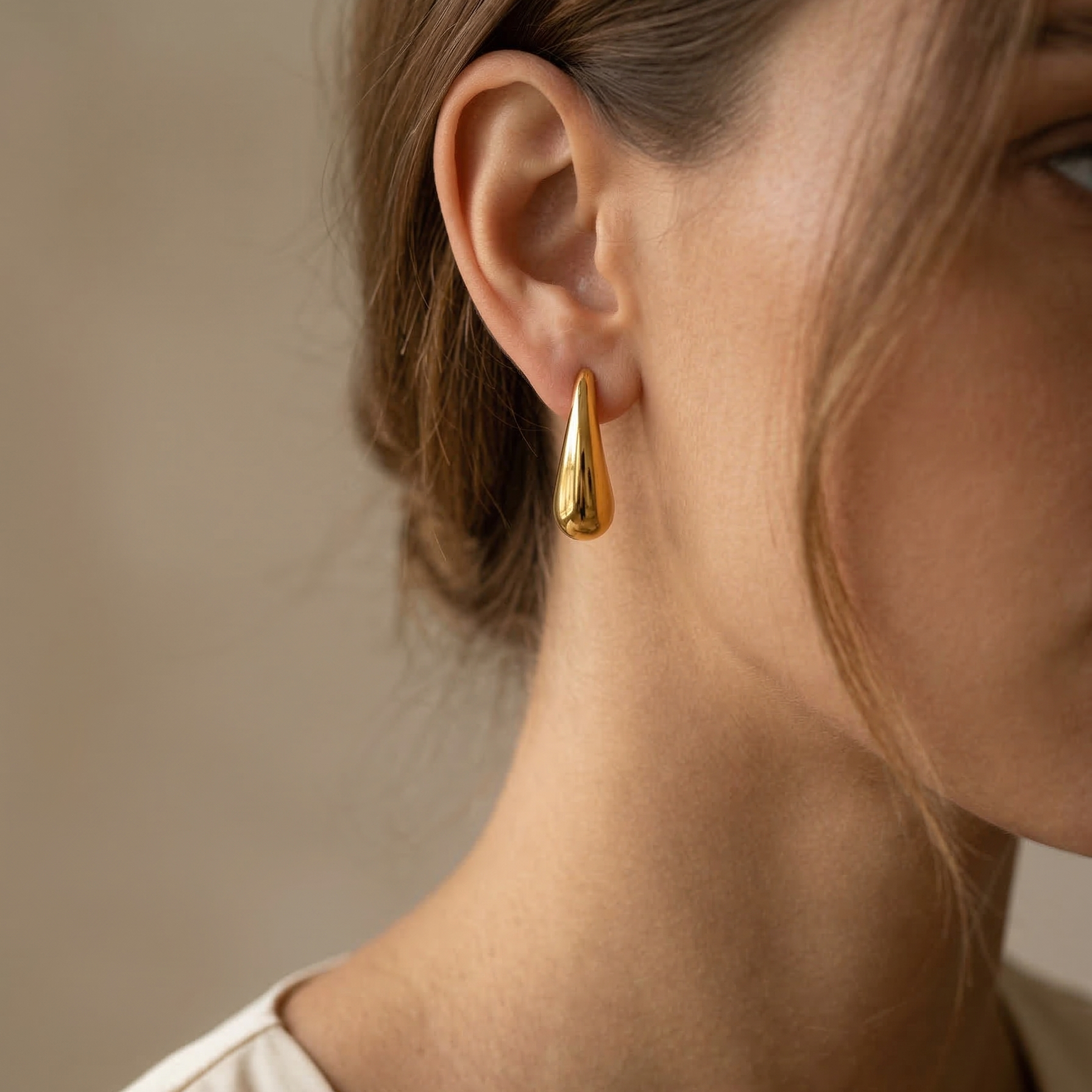 Gold earring worn by a person with a neutral background