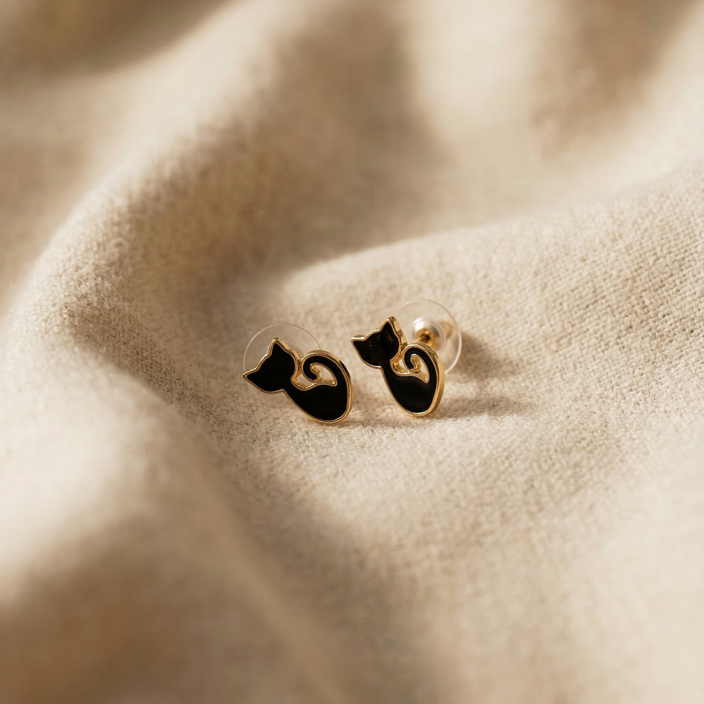 Cat-shaped earrings on a soft fabric background