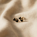 Cat-shaped earrings on a soft fabric background