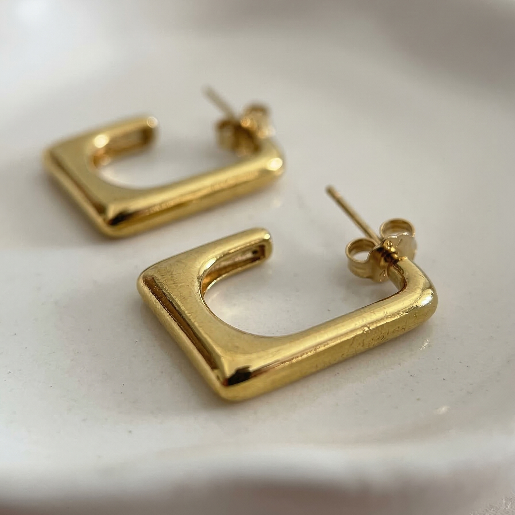 Gold hoop earrings on a white dish