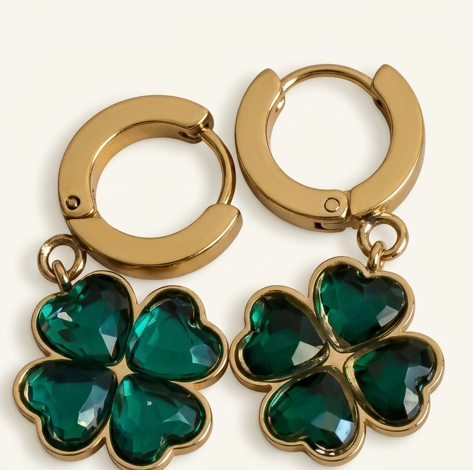 Gold hoop earrings with green four-leaf clover charms on a white background