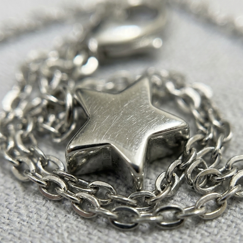Silver chain necklace with a star pendant on a gray background
