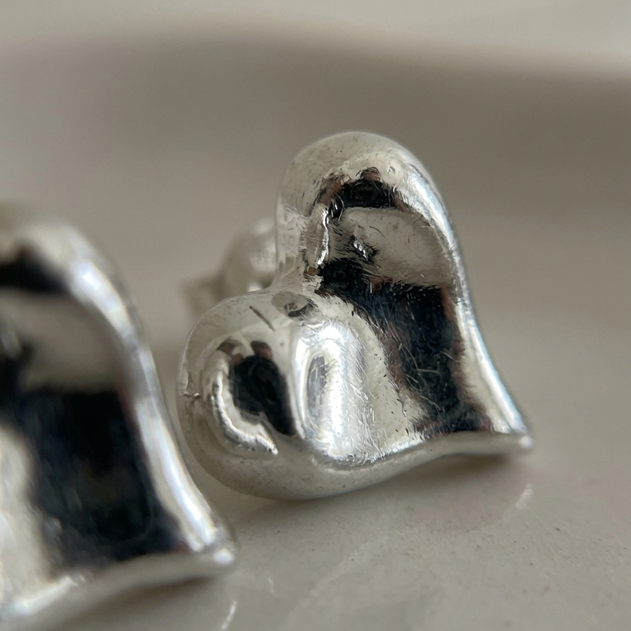 Close-up of silver heart-shaped earrings on a light background