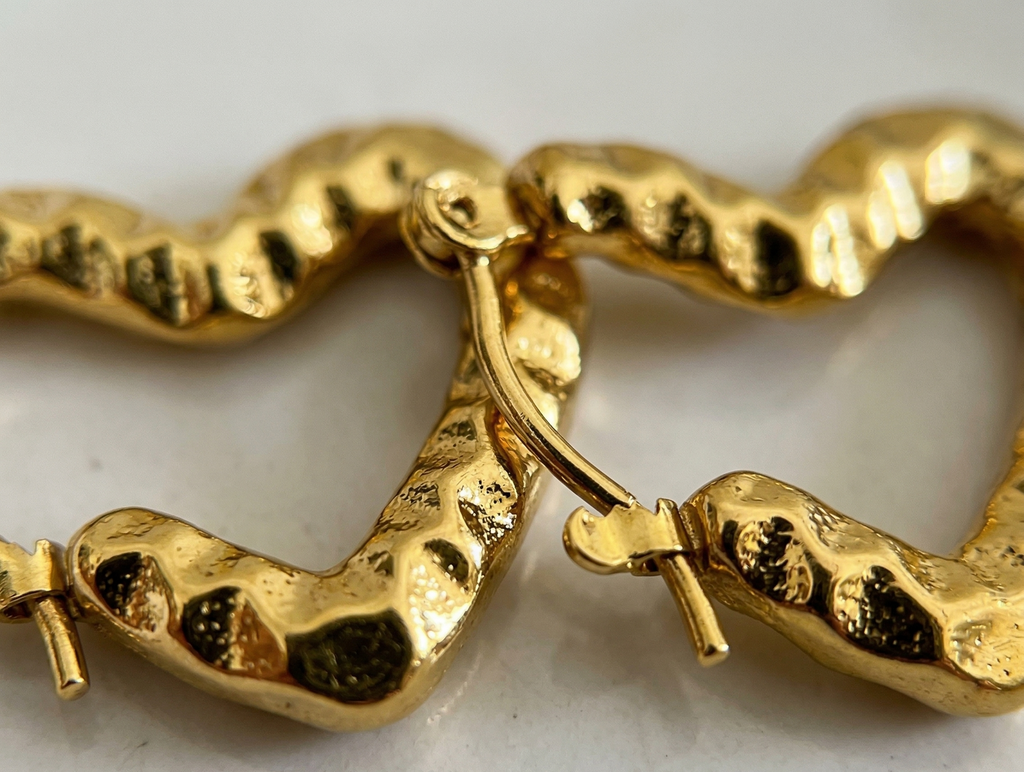 Gold heart-shaped hoop earrings on a light background