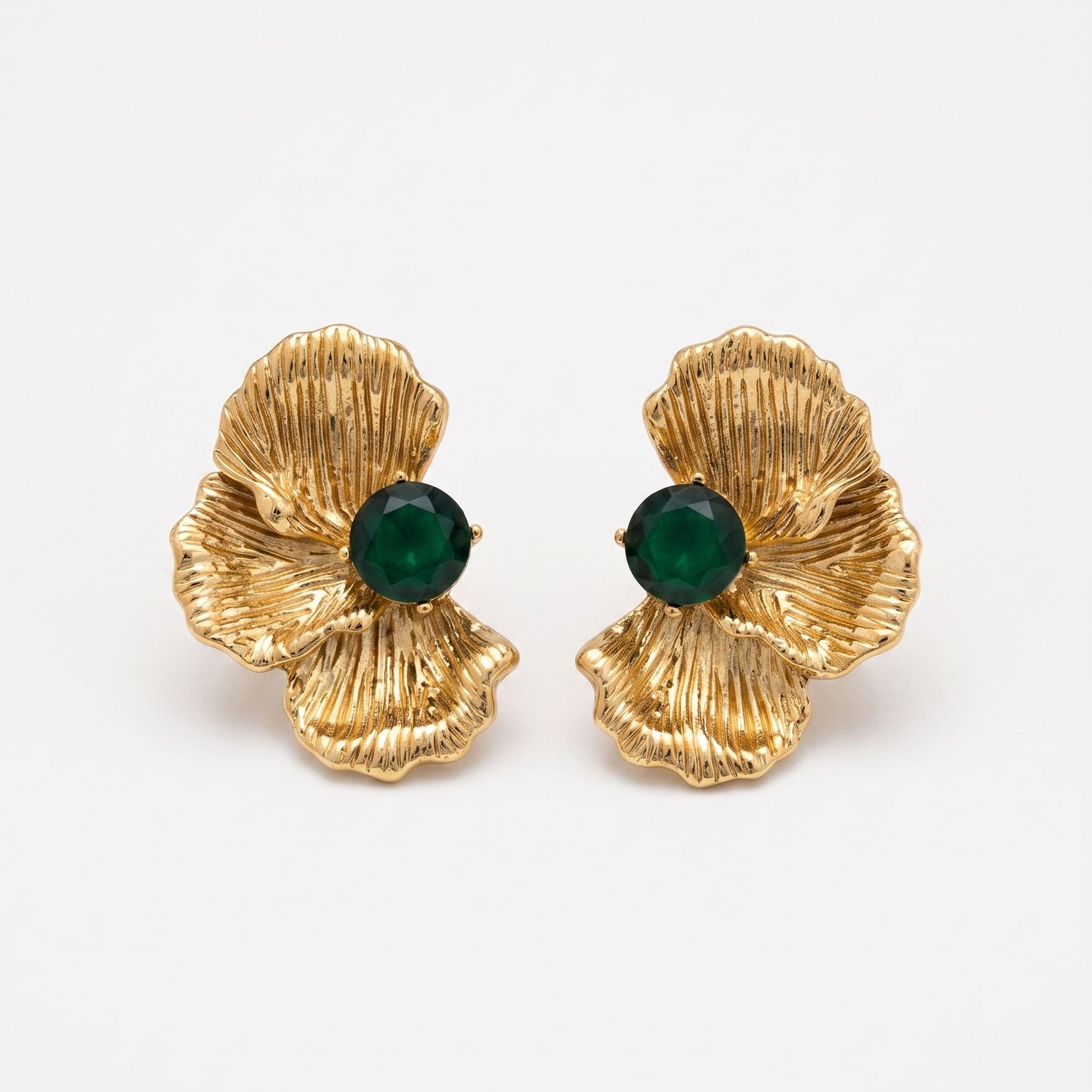 Gold earrings with green gemstones on a white background