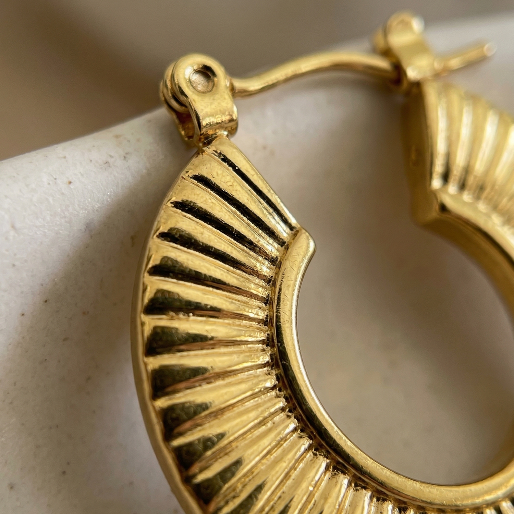 Gold hoop earring on a beige surface