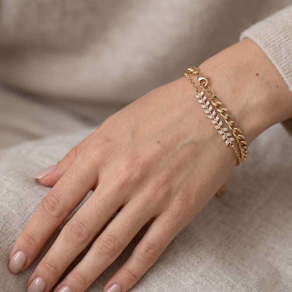 Gold chain bracelet on a hand against a neutral background