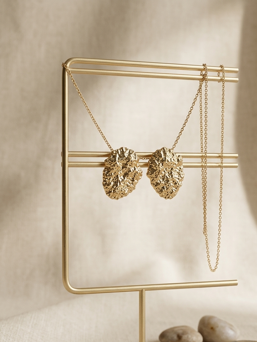 Gold necklace on a gold stand with pebbles on a beige background