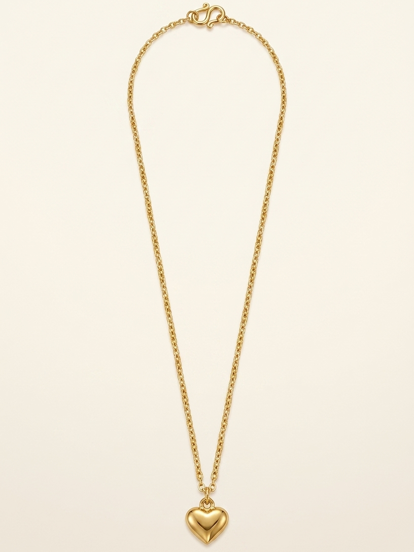 Gold necklace with a heart pendant on a beige background