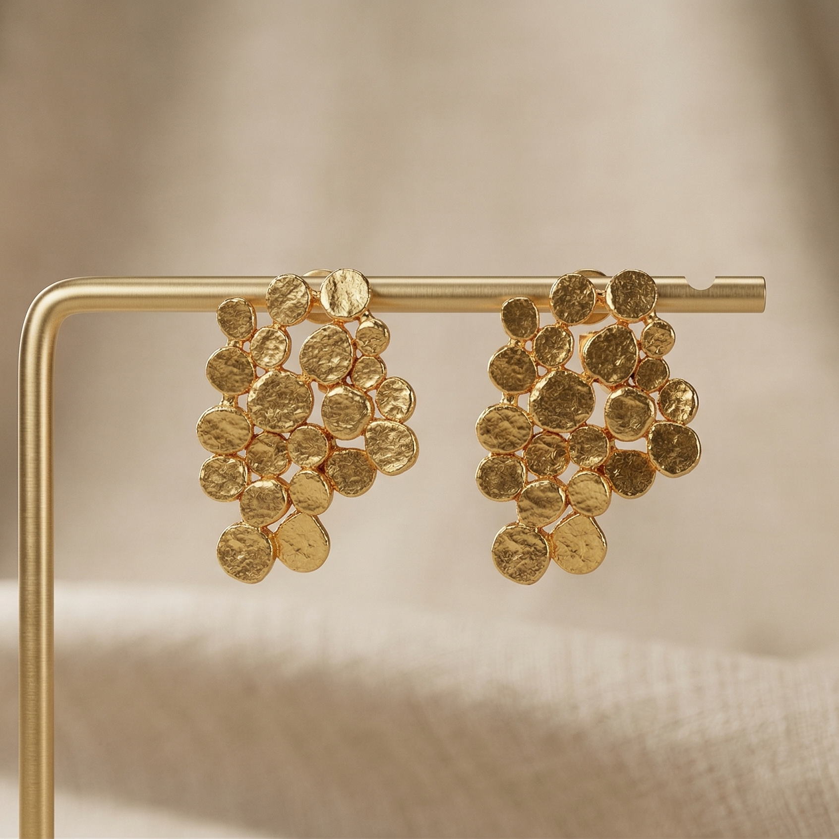 Gold earrings on a gold stand against a beige background