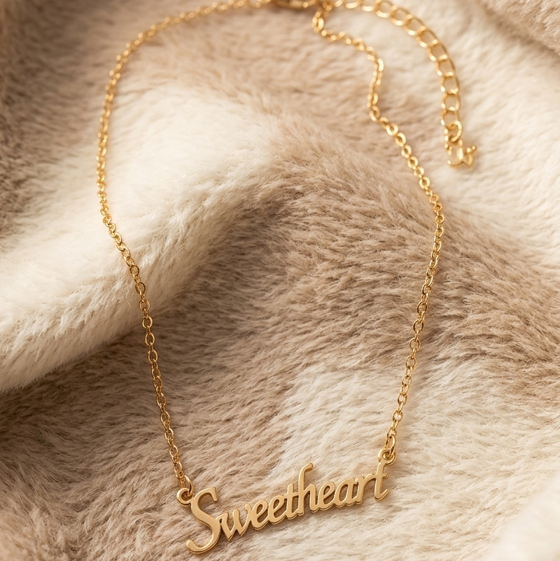 Gold 'Sweetheart' bracelet on a soft, beige fabric background