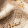 Gold 'Sweetheart' bracelet on a soft, beige fabric background
