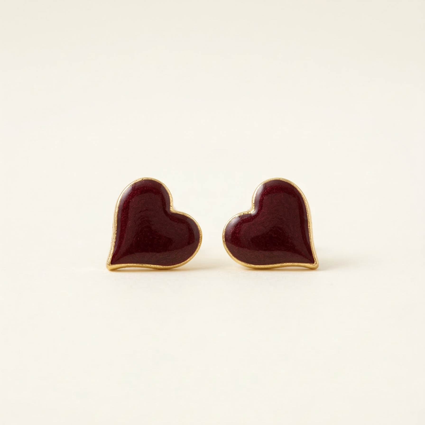 Heart-shaped earrings with gold rims on a beige background