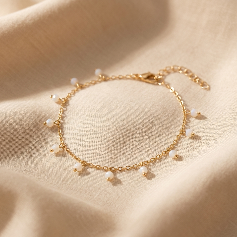 Gold bracelet with small pearls on a beige fabric background