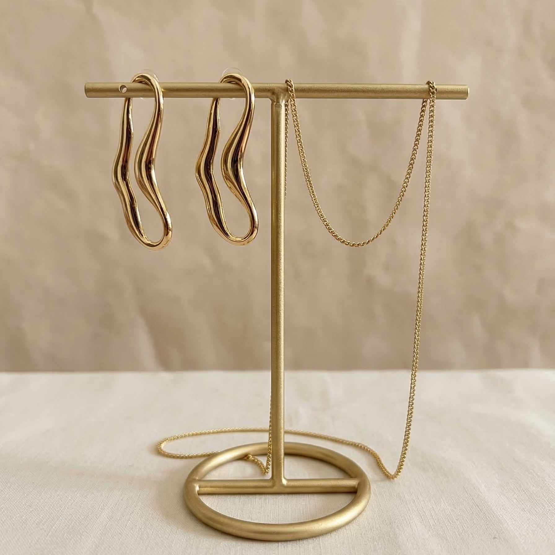 Gold earring stand with hanging earrings on a beige background