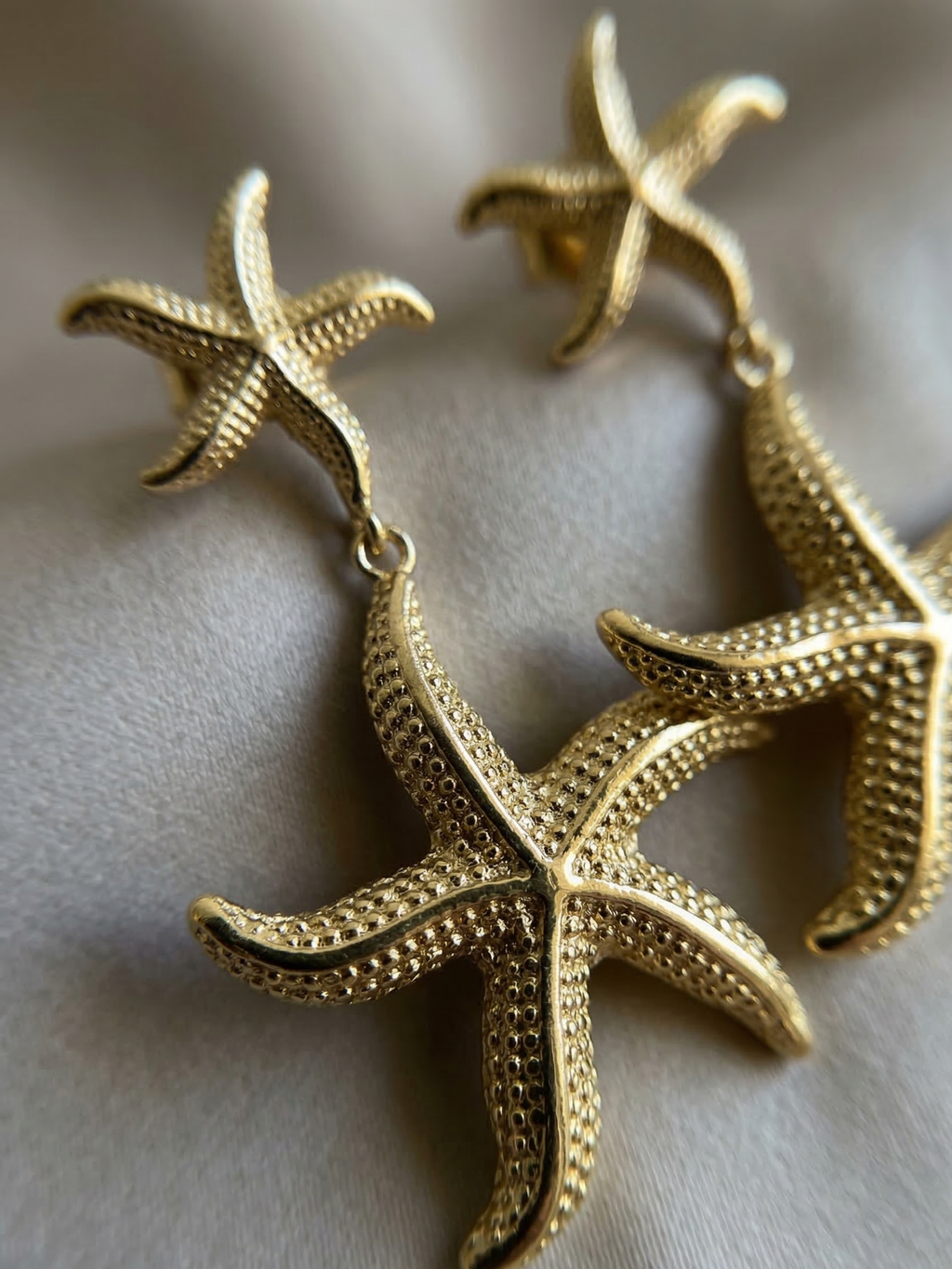 Gold starfish-shaped earrings on a light gray background