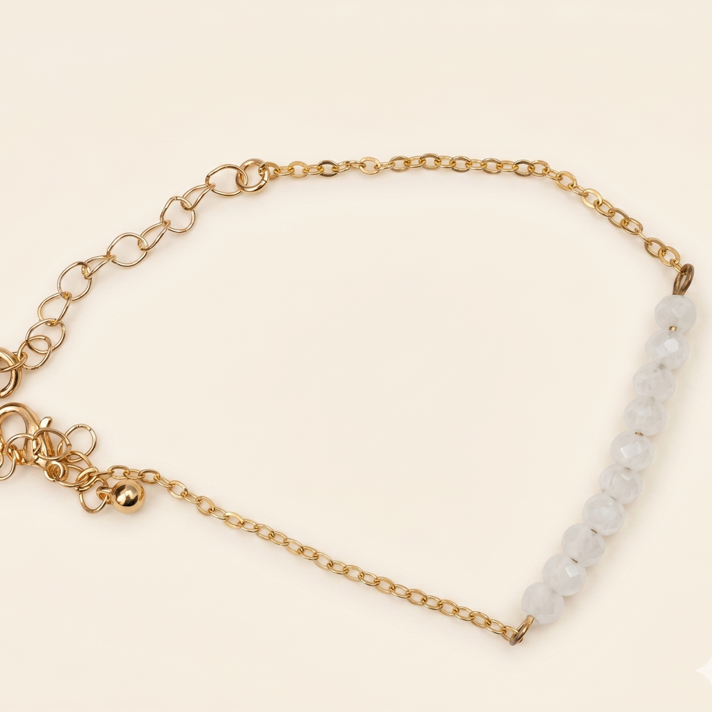 Gold bracelet with white beads on a beige background