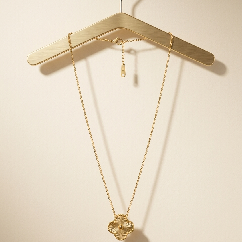 Gold necklace on a wooden hanger against a beige background
