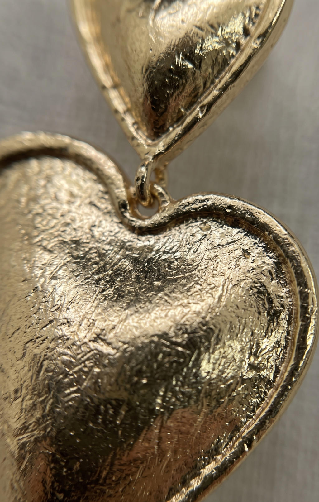 Close-up of a gold heart-shaped pendant on a metallic background