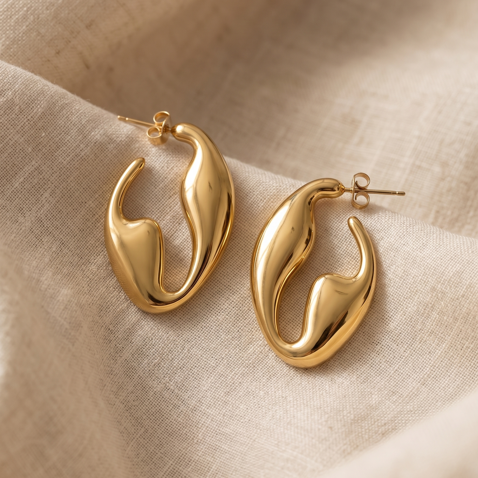 Gold hoop earrings on a beige fabric background