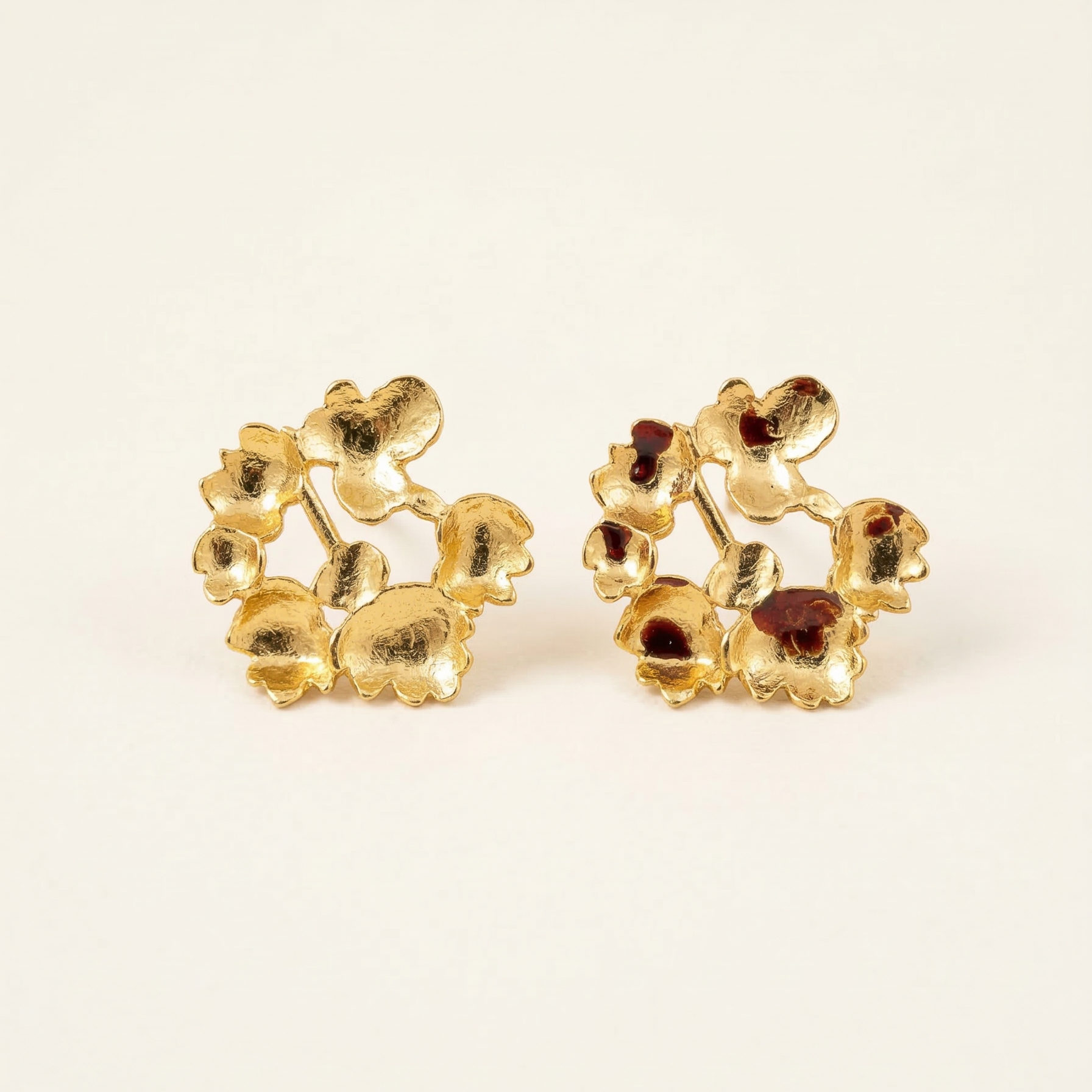 Pair of gold floral earrings on a beige background