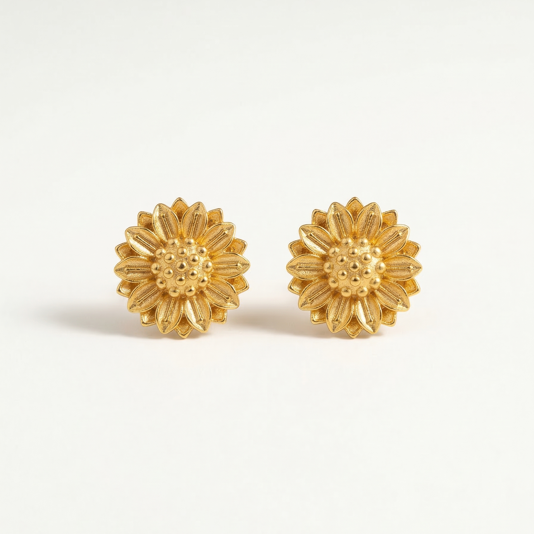 Gold flower-shaped earrings on a white background