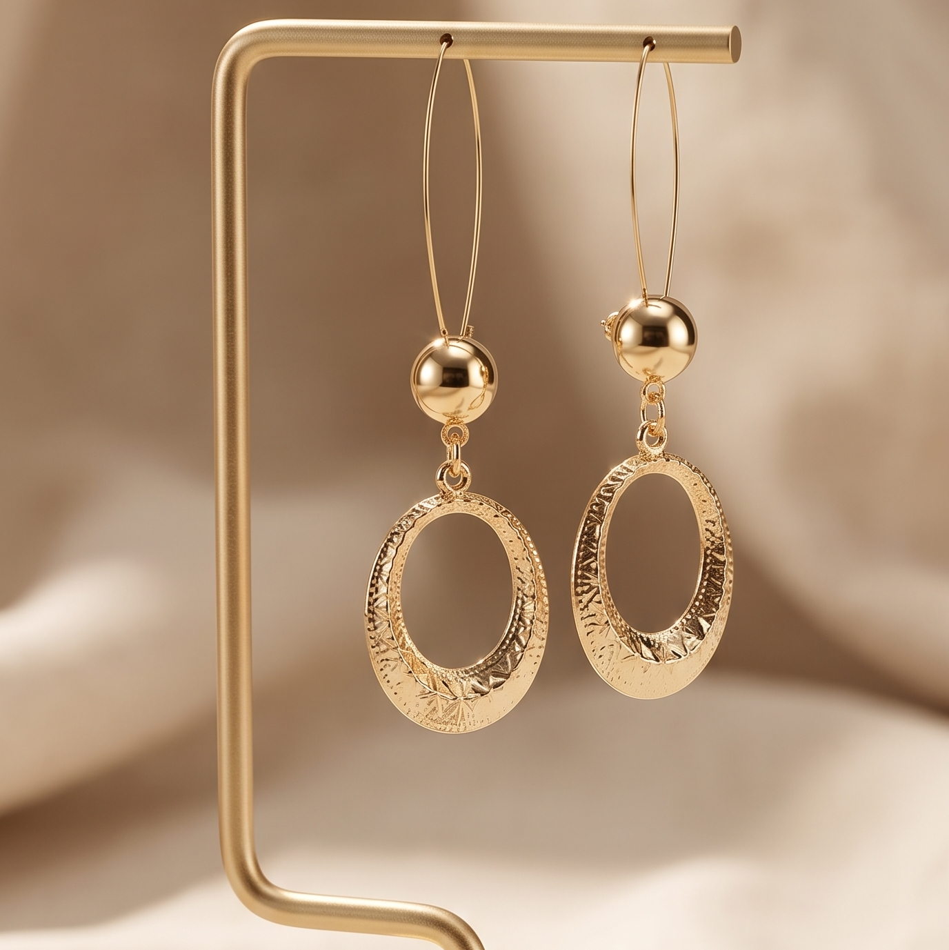 Gold hoop earrings on a gold stand against a beige background
