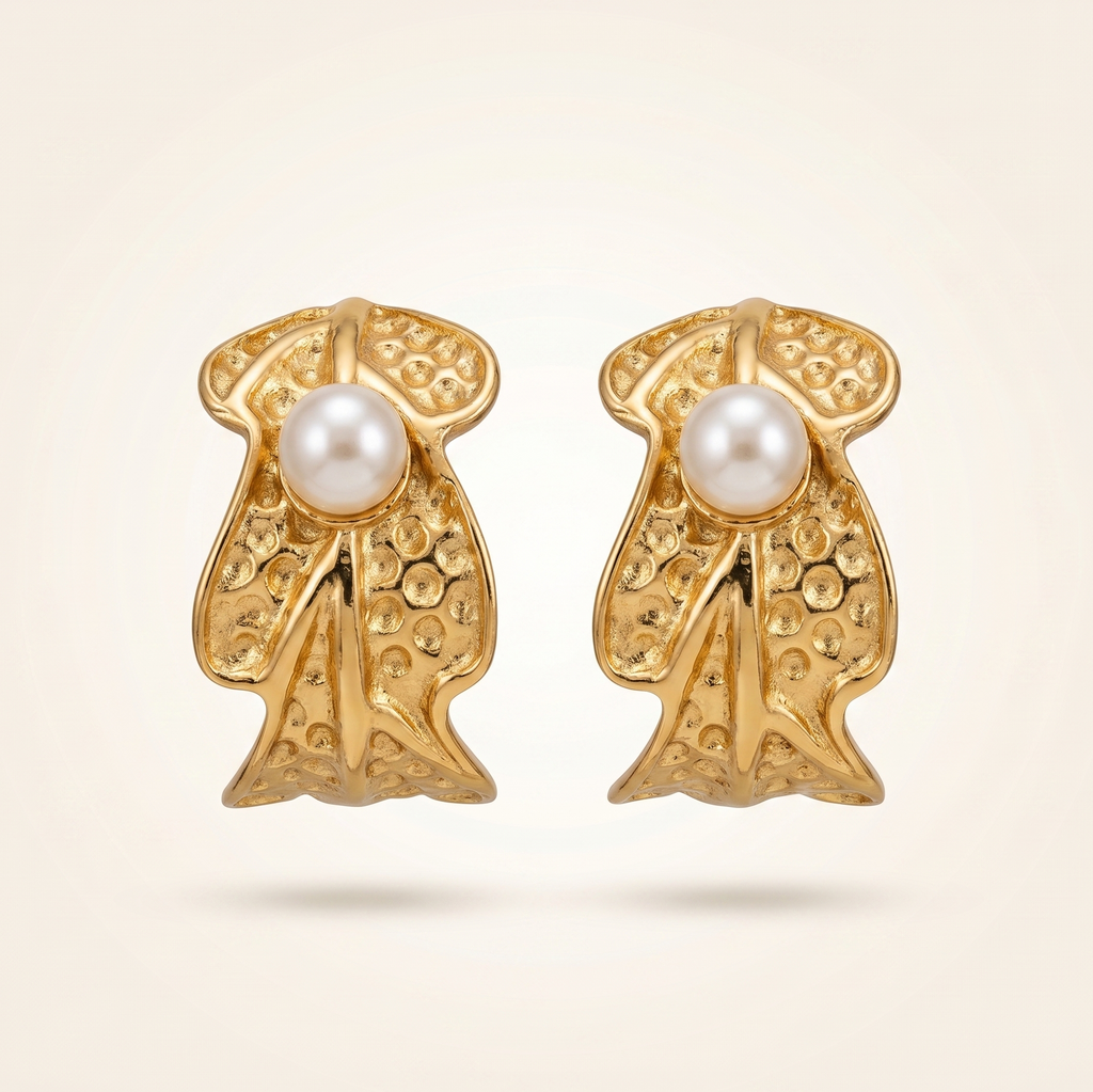 Gold earrings with pearl centers on a beige background