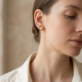 Close-up of a woman wearing pearl earrings with a neutral background