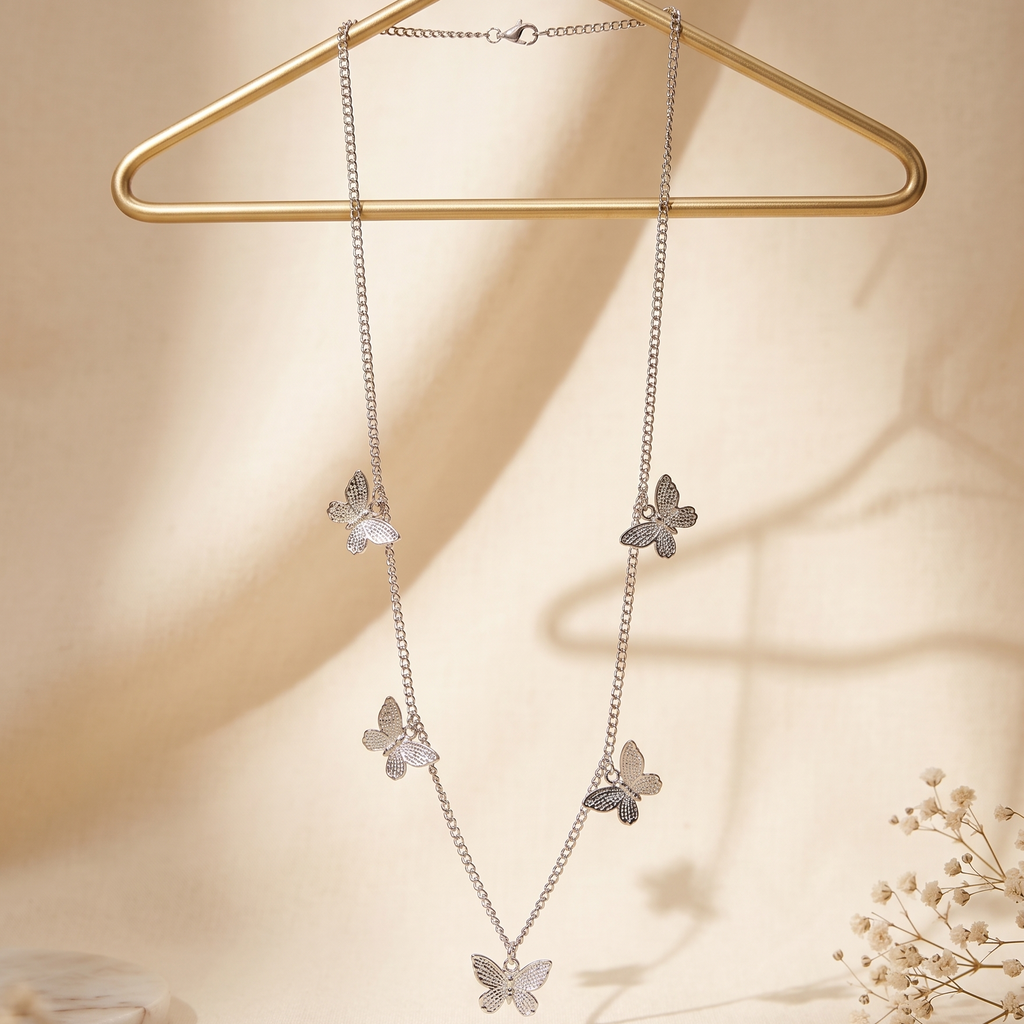 Butterfly-themed necklace on a gold hanger against a beige background