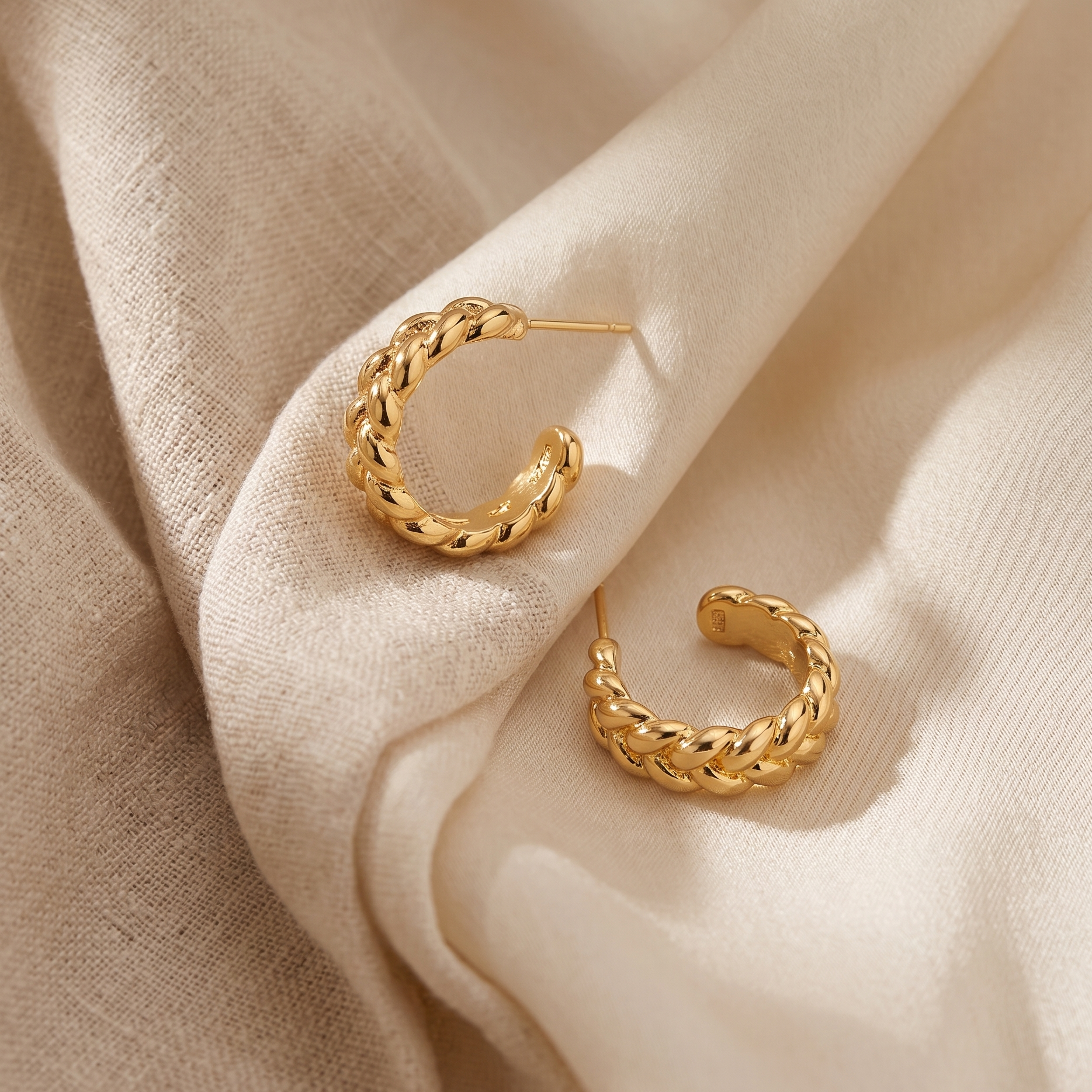 Gold hoop earrings on beige fabric