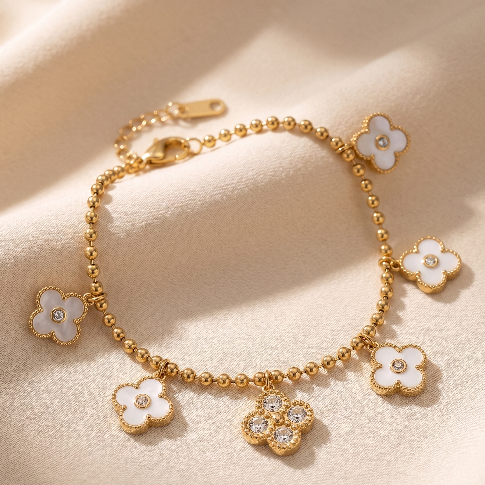 Gold bracelet with floral charms on a beige fabric background