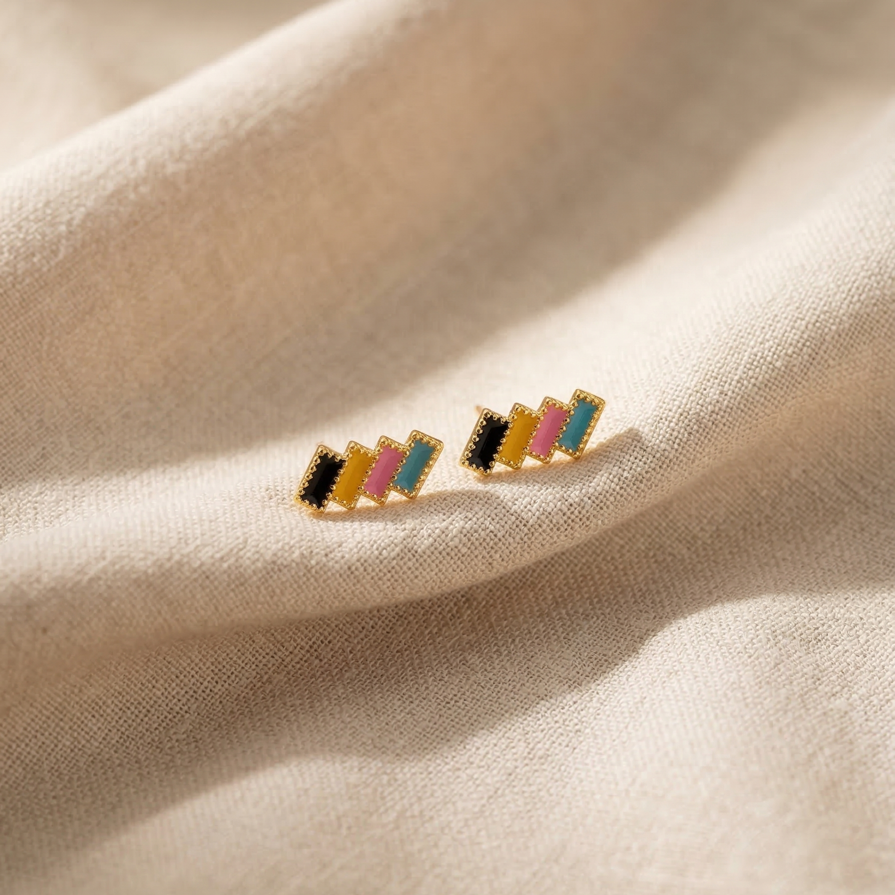 Multicolored striped earrings on a beige fabric background