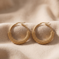 Gold hoop earrings on a beige fabric background