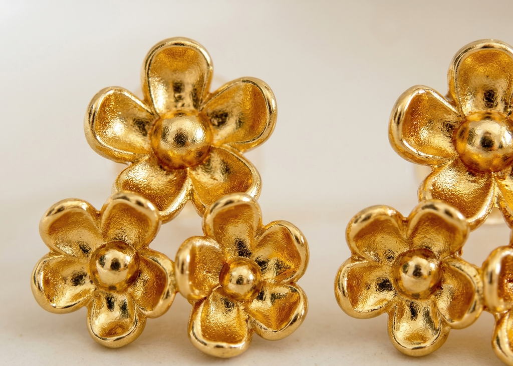 Gold flower-shaped earrings on a light background