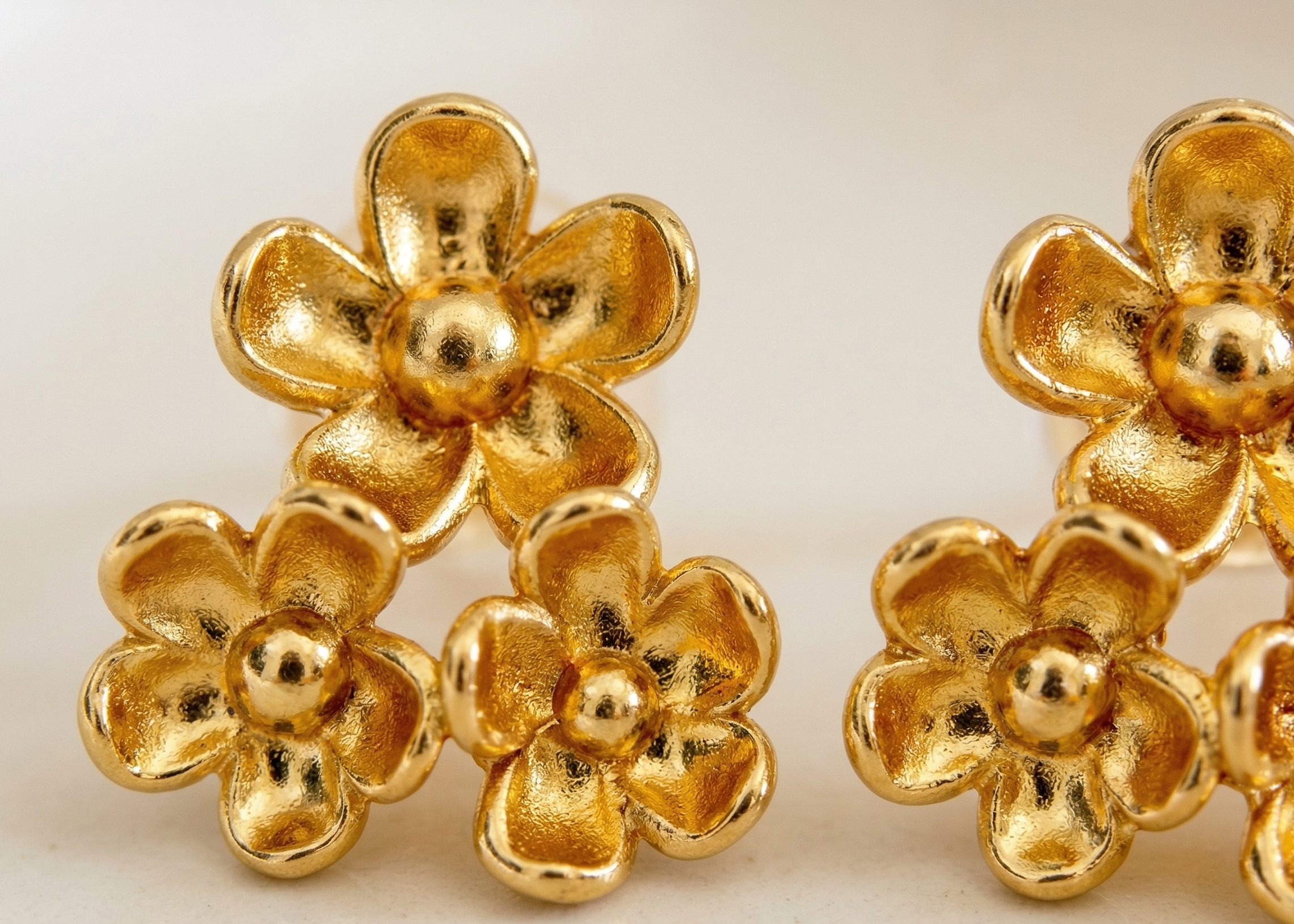 Gold flower-shaped earrings on a light background