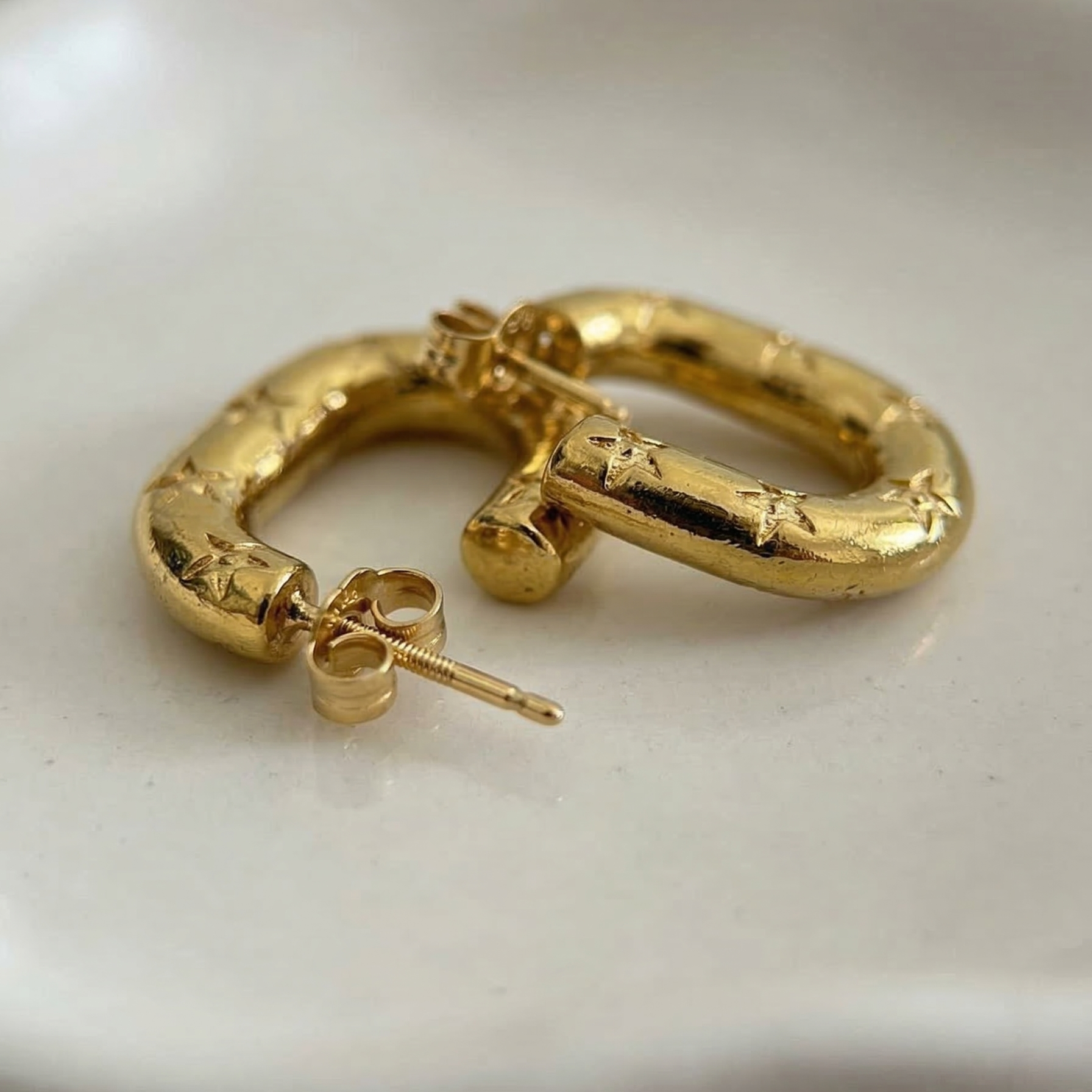 Gold hoop earrings on a white dish