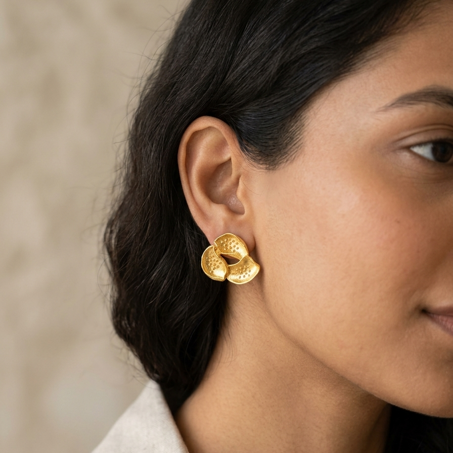 Close-up of a woman wearing gold earrings with a neutral background