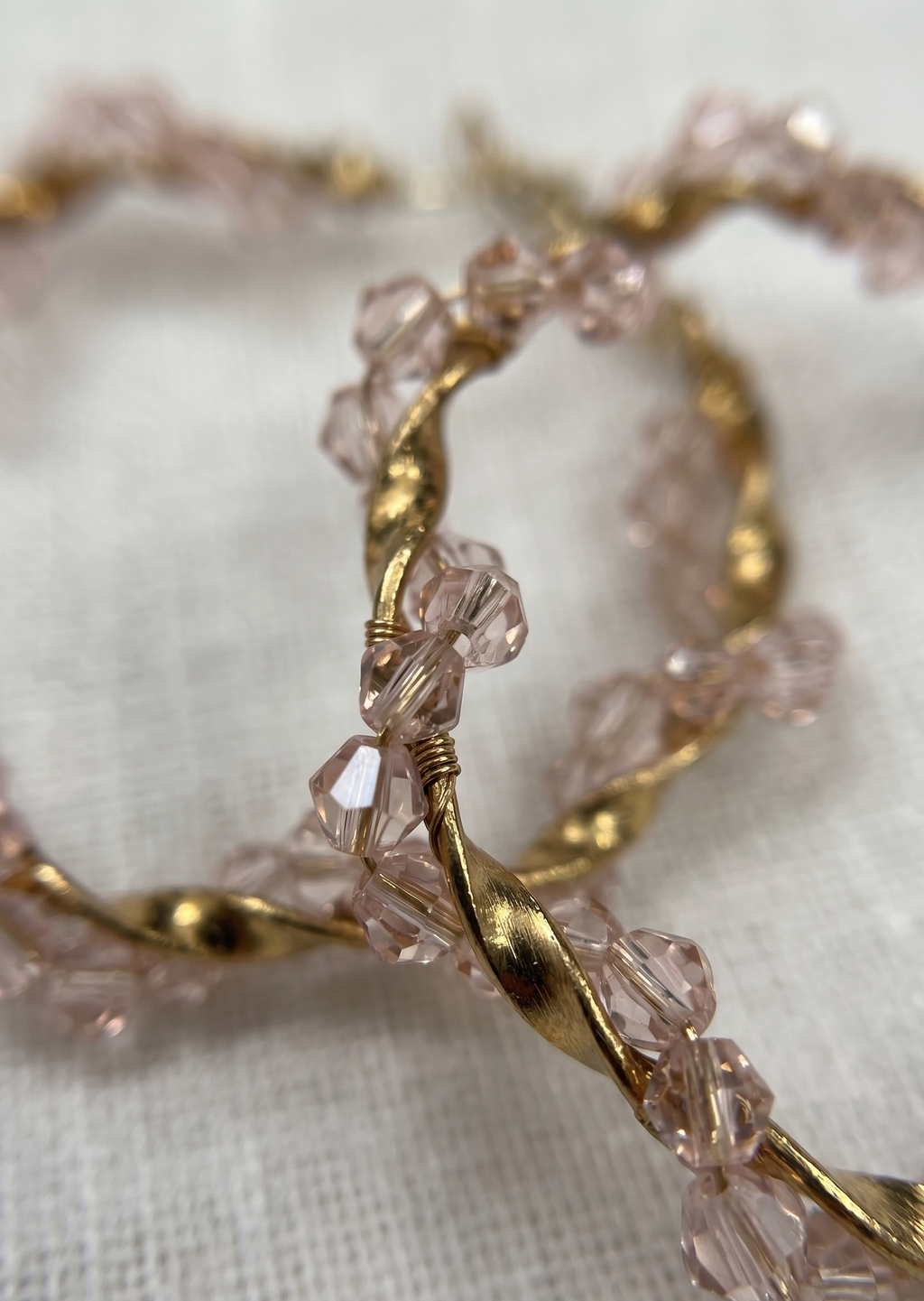 Gold hoop earrings with pink beads on a light background