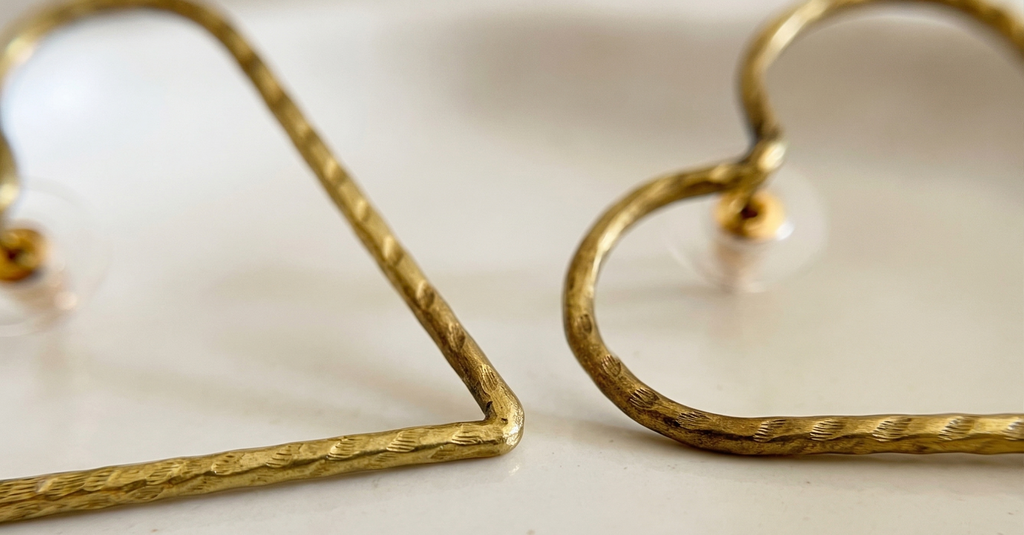 Gold heart-shaped earrings on a light background