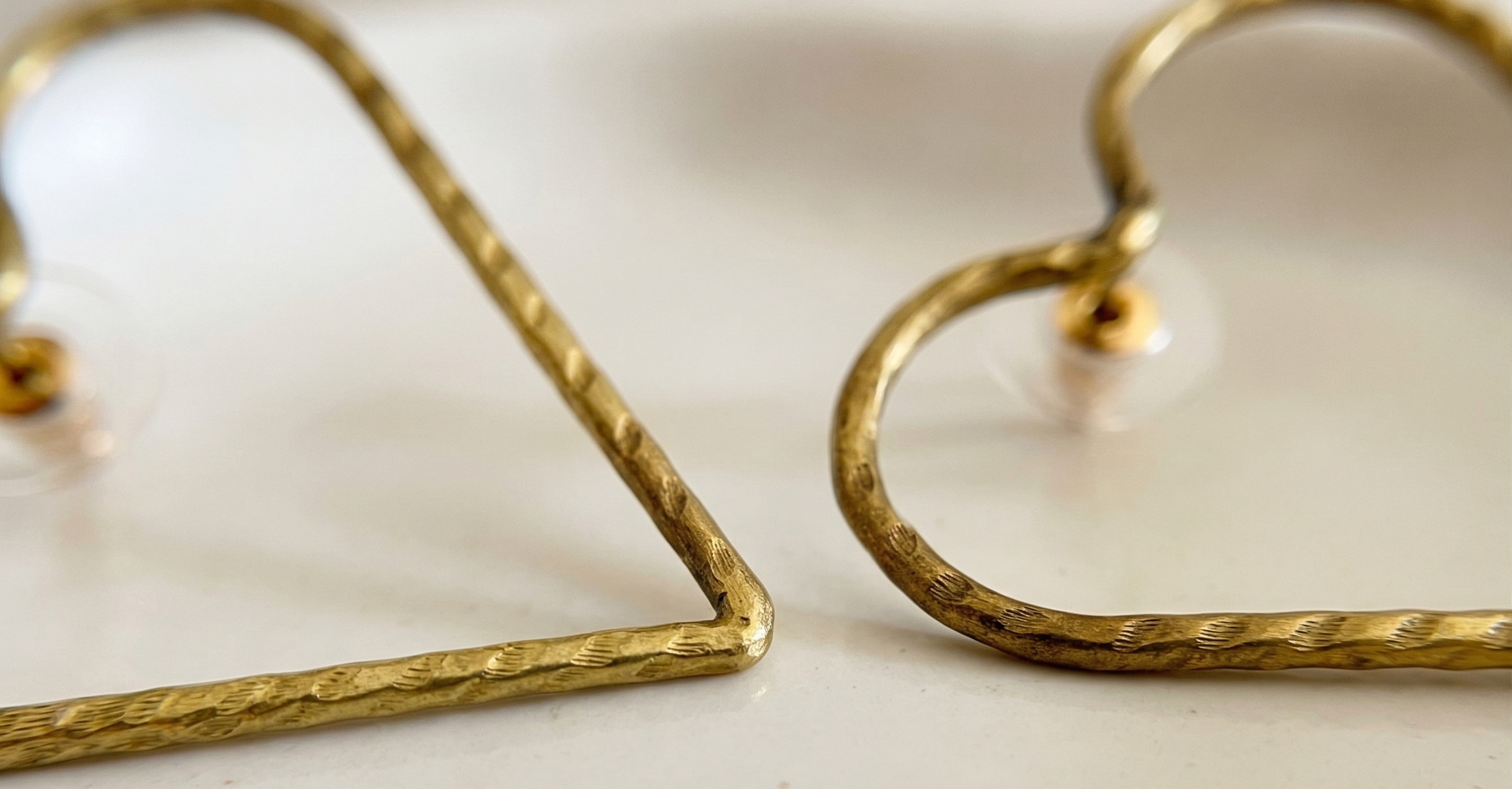 Gold heart-shaped earrings on a light background