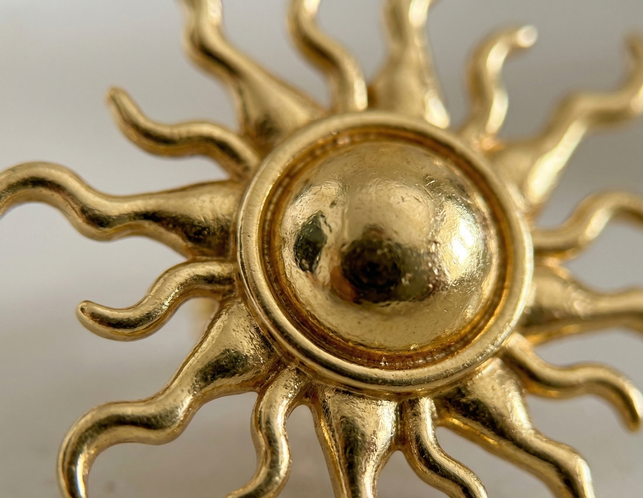 Gold sun-shaped decorative item on a white background